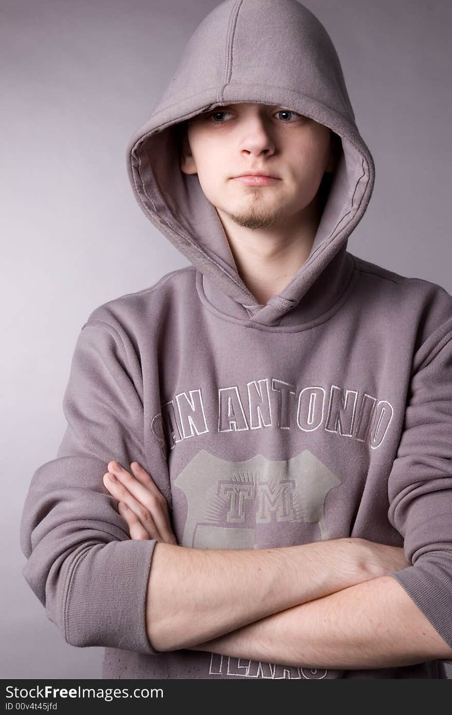 The young guy in a hood in studio on a grey background