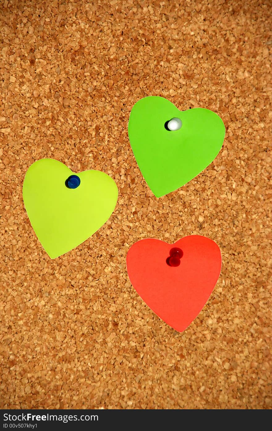 3 colored notes in form of a heart in a cork board. 3 colored notes in form of a heart in a cork board