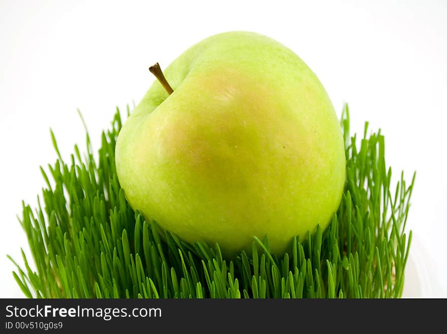 Green apple on grass isolated onwhite