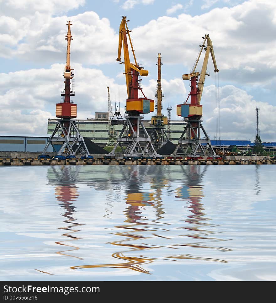 Container cranes for loading and unloading ships. Reflection over water.