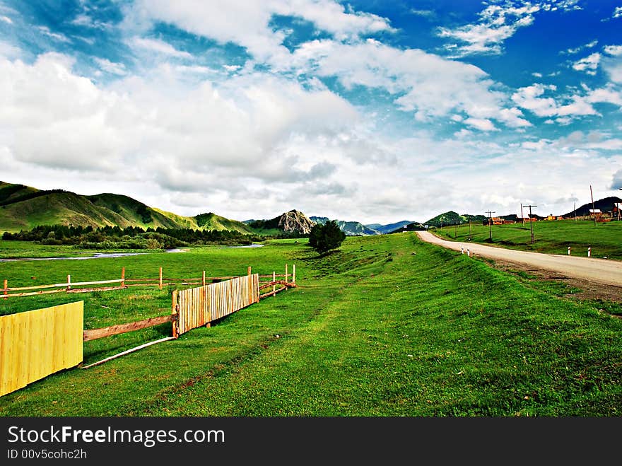 Rural scene, country background, summer, green grass and blue sky with clouds, road to horizon, valley of village, farm pasture