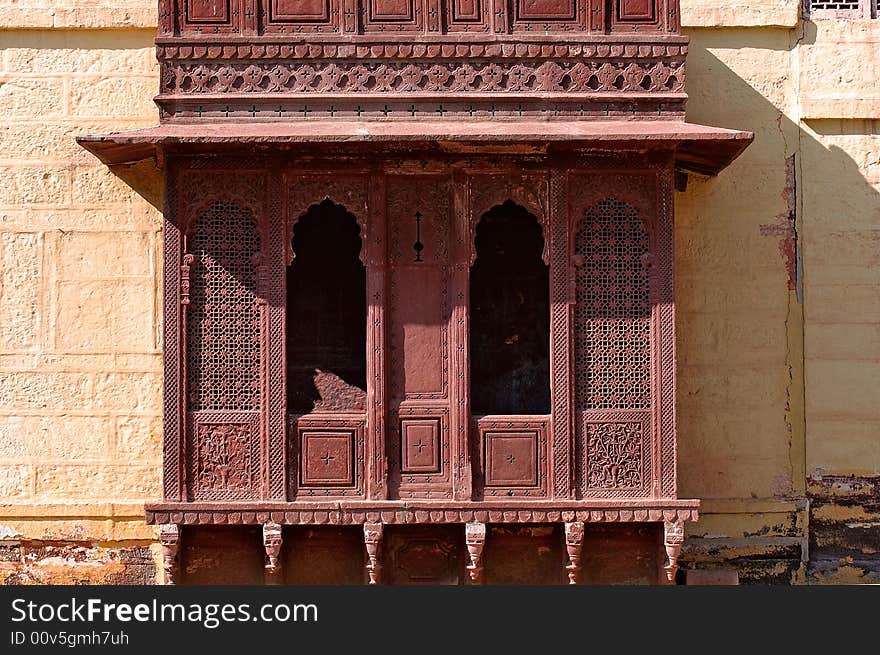 India, Jaisalmer: Indian palace architecture; red walls and wooden carved frame and window