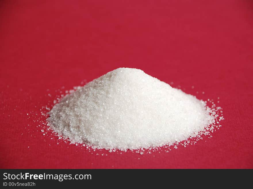 Heap of white sugar on a red background