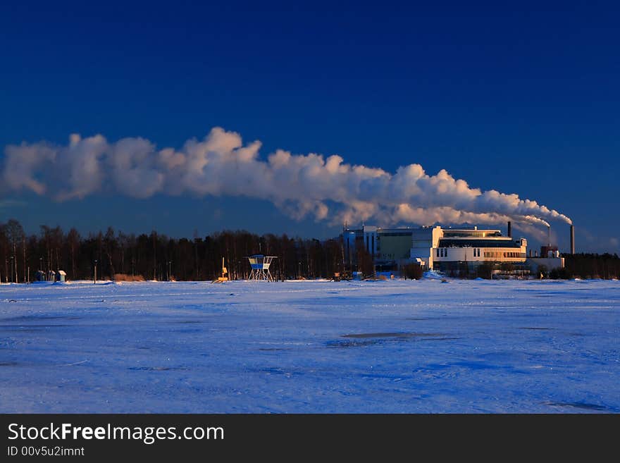 Factory smoke on blue sky in winter sunset