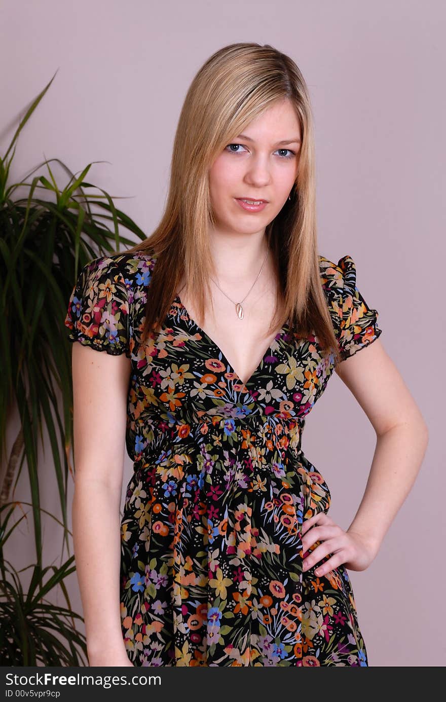 Portrait of attractive young girl standing posing in floral dress in contemporary home. Portrait of attractive young girl standing posing in floral dress in contemporary home