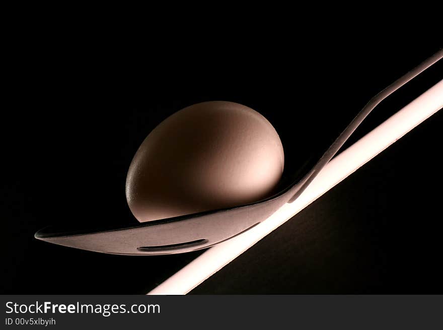 Egg on black plastic spoon with slits on black background. Egg on black plastic spoon with slits on black background.