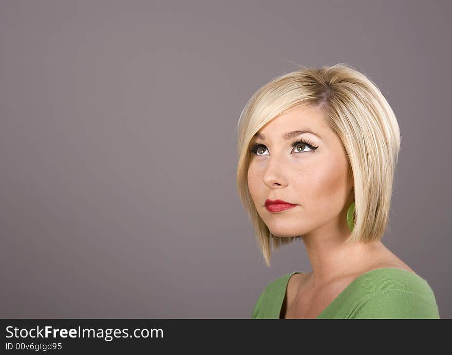 A blonde model in green blouse looking up and to the side. A blonde model in green blouse looking up and to the side