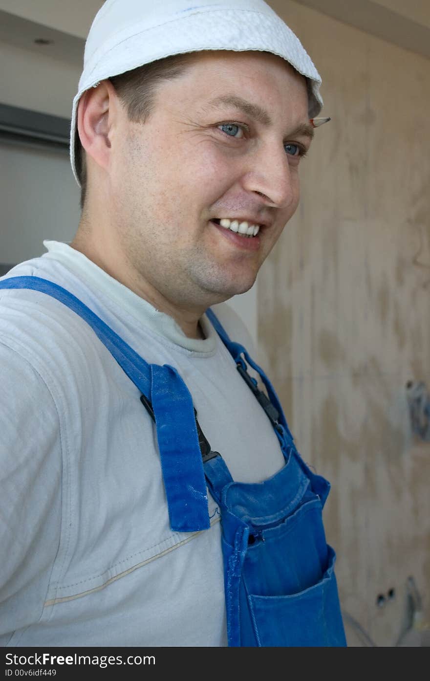 Smiling builder wearing a hat and a blue coverall