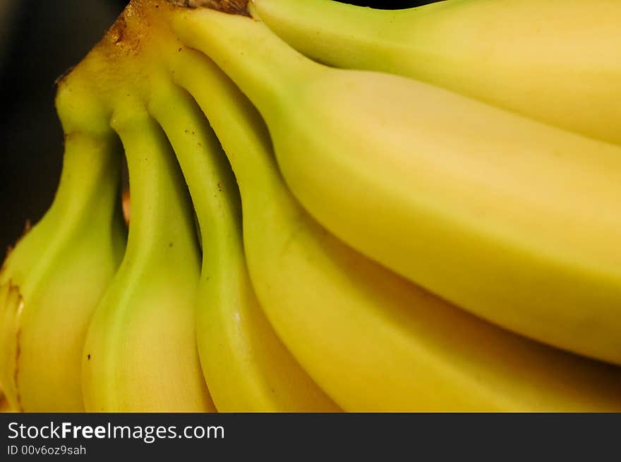 A bunch of yellow bananas against a black background. A bunch of yellow bananas against a black background.