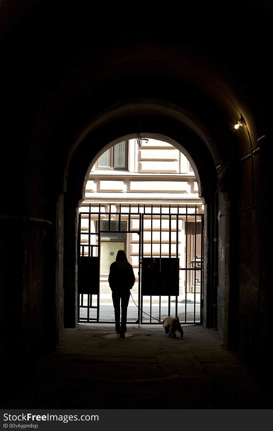 Girls with dog goes on street through archway. Girls with dog goes on street through archway