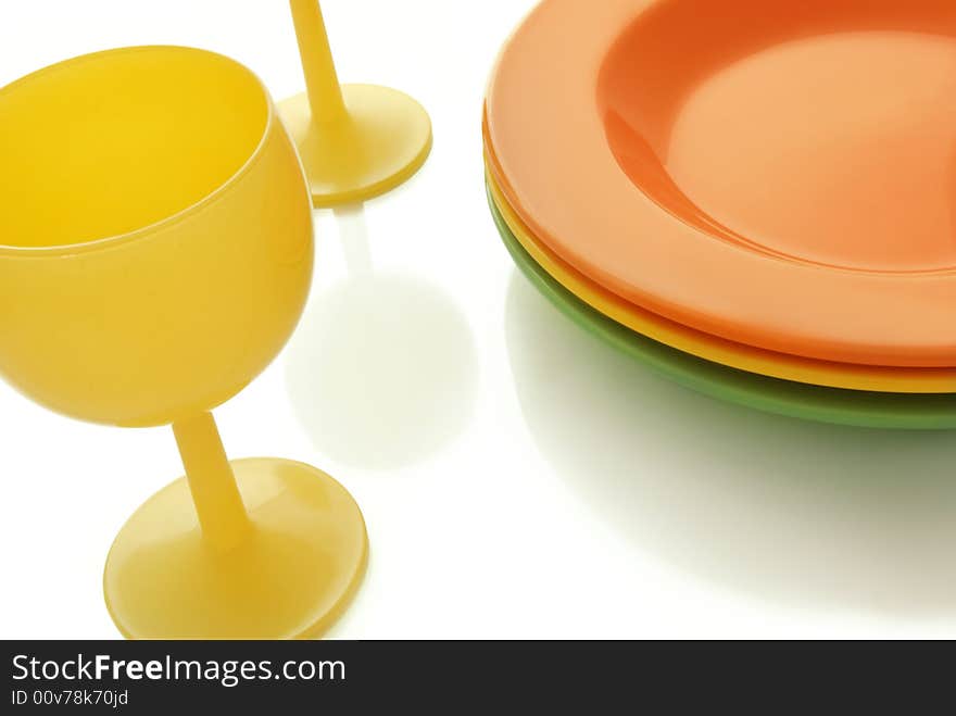 Closeup of a place setting with color ceramic plates and a wine glass. Closeup of a place setting with color ceramic plates and a wine glass