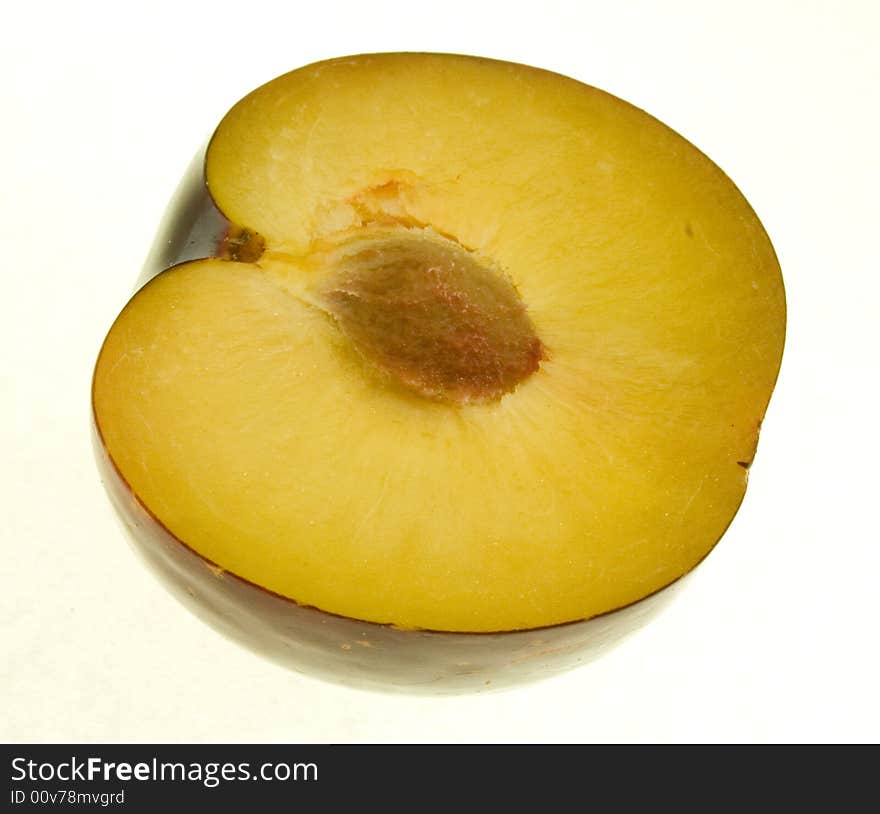 Plum half showing stone on white background