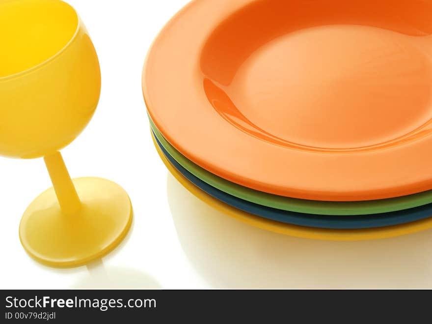 Closeup of a place setting with color ceramics plates and a wine glass. Closeup of a place setting with color ceramics plates and a wine glass