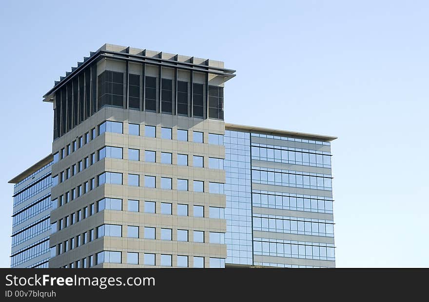 A modern blue glass and concrete building in a clear blue sky