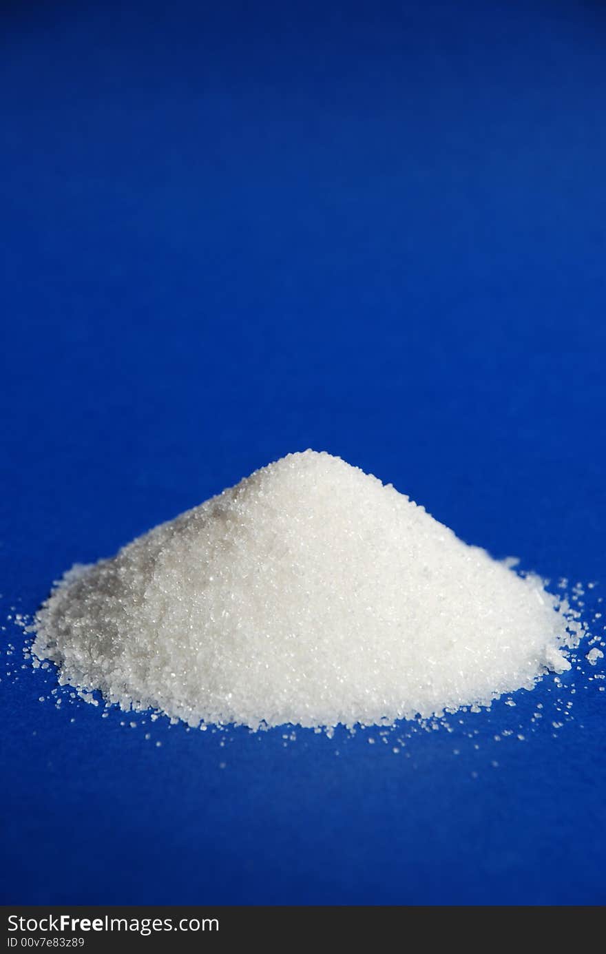 Heap of white sugar on a blue background