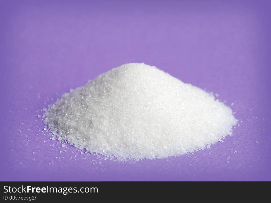 Heap of white sugar on a violet background