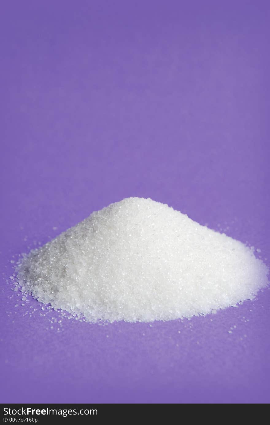 Heap of white sugar on a violet background