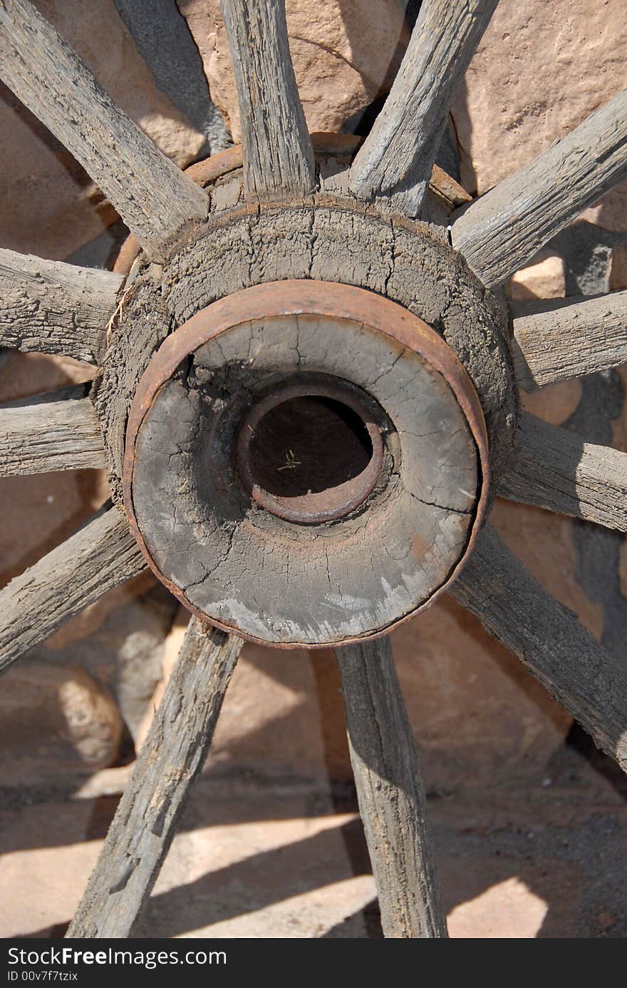 Wooden wagon wheel against stone wall closeup