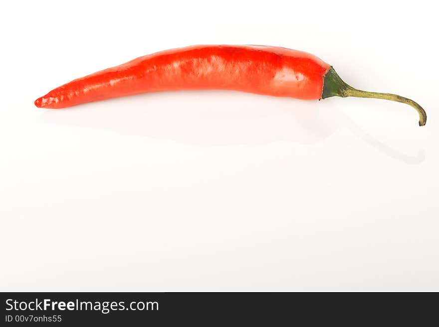 Isolated on white red hot chili pepper laying on the smooth surface with reflection. Isolated on white red hot chili pepper laying on the smooth surface with reflection