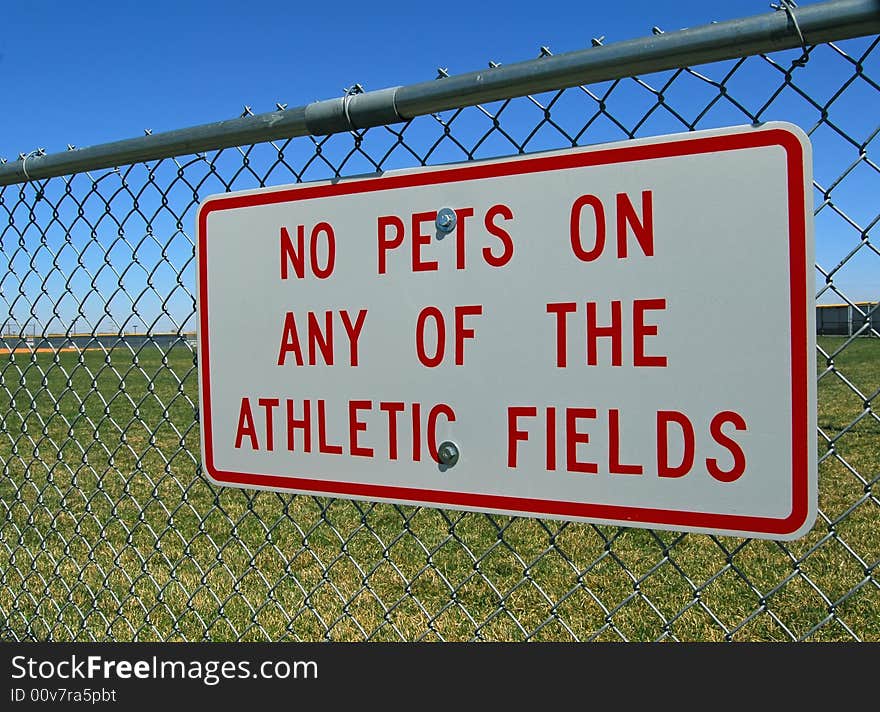 Sign on chain link fence forbidding pets on athletic fields. Sign on chain link fence forbidding pets on athletic fields.