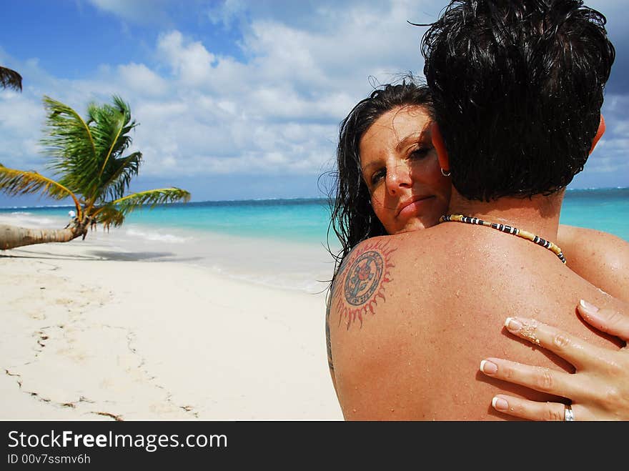 Woman hugging a man while peering over his shoulder in a tropical location. Woman hugging a man while peering over his shoulder in a tropical location.