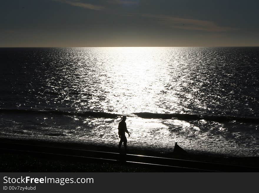 Man walking on beach at sunset. Man walking on beach at sunset.