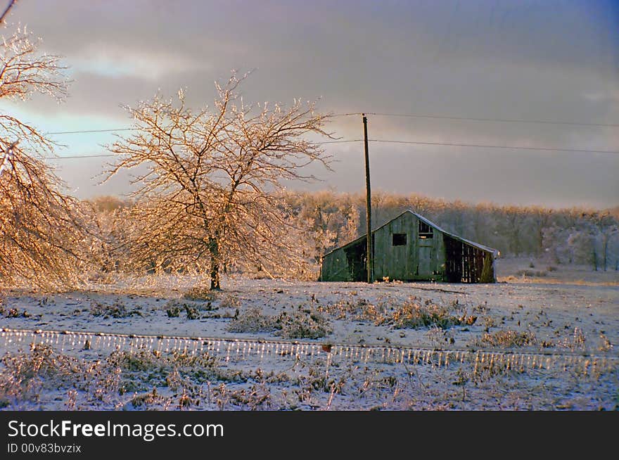 Sun setting on the aftermath of an ice storm with ice encrusted trees and old building. Sun setting on the aftermath of an ice storm with ice encrusted trees and old building