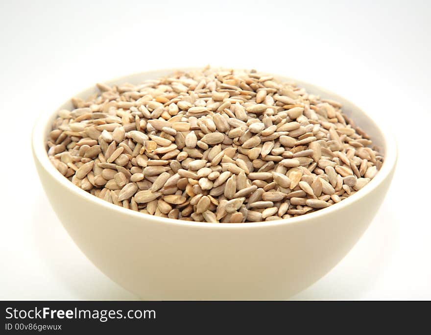 Sunflower seeds in a cream bowl against a white background