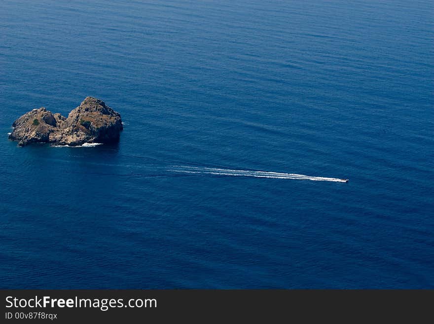 Small rock island in Ionian sea and speed boat cruising. Small rock island in Ionian sea and speed boat cruising