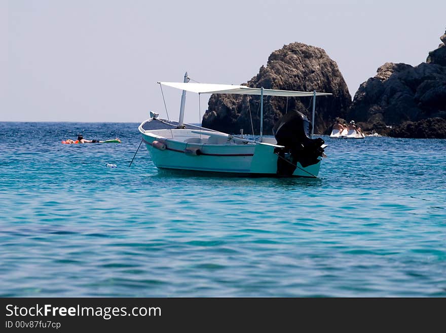 People relaxing in the blue sea near a boat. People relaxing in the blue sea near a boat