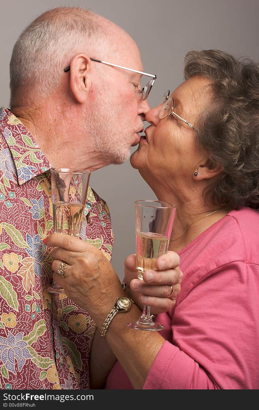 Happy Senior Couple Kissing while holding Champagne glasses.