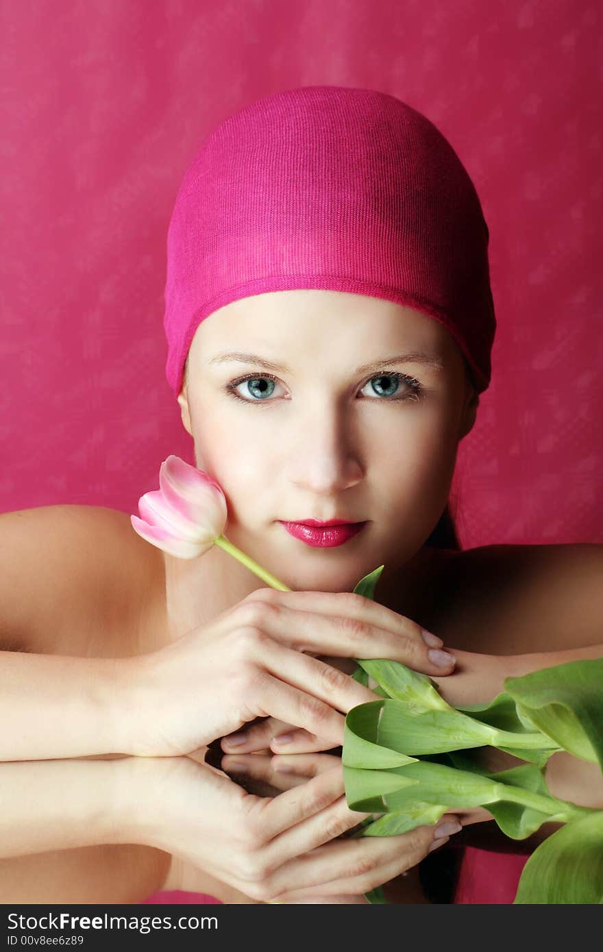 Beauty portrait of a young woman in pink with a tulip flower on a mirror. Beauty portrait of a young woman in pink with a tulip flower on a mirror