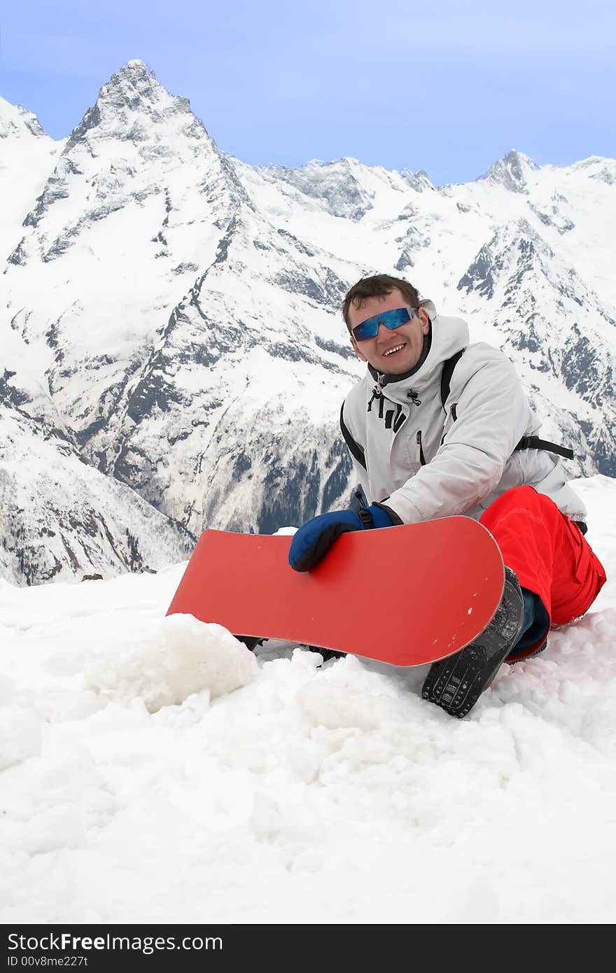 Happy man with red snowboard in mountains. Happy man with red snowboard in mountains