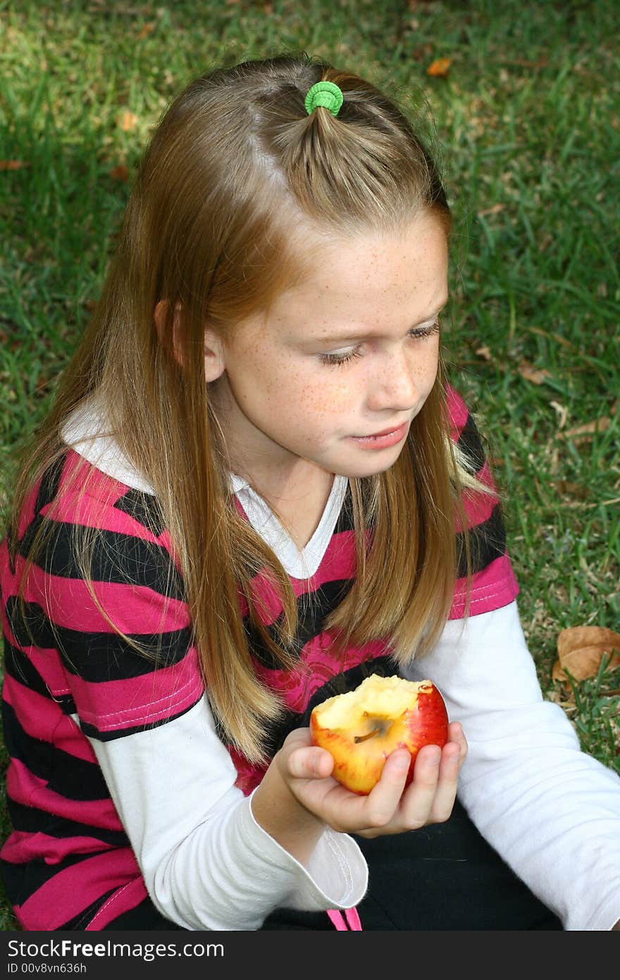 A white caucasian girl child holding a half eaten apple in her hand. A white caucasian girl child holding a half eaten apple in her hand