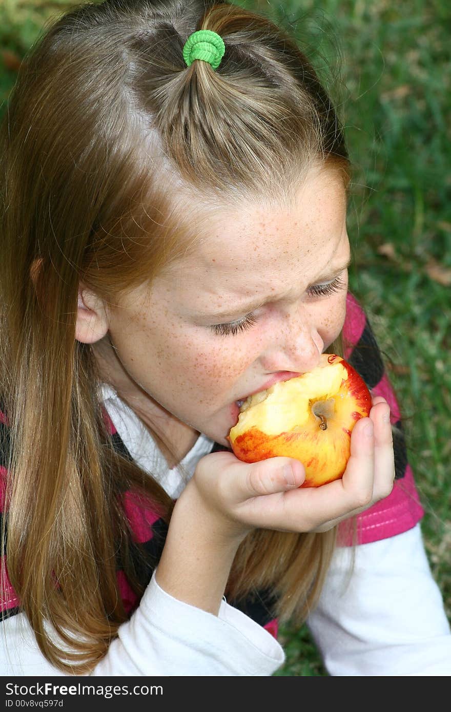 A white caucasian girl child taking a bite of a fresh juicy apple. A white caucasian girl child taking a bite of a fresh juicy apple