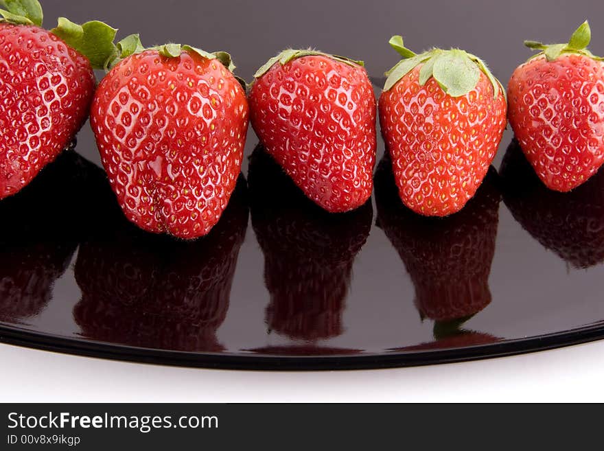 Five ripe strawberries on the black plate. Five ripe strawberries on the black plate