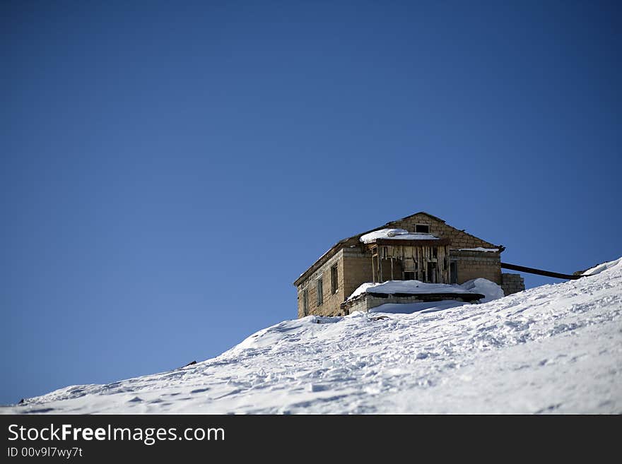 Abandoned house in high mountains, blue sky, winter