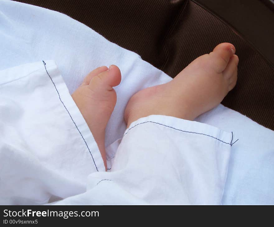 Small legs sleeping baby on white bedsheet