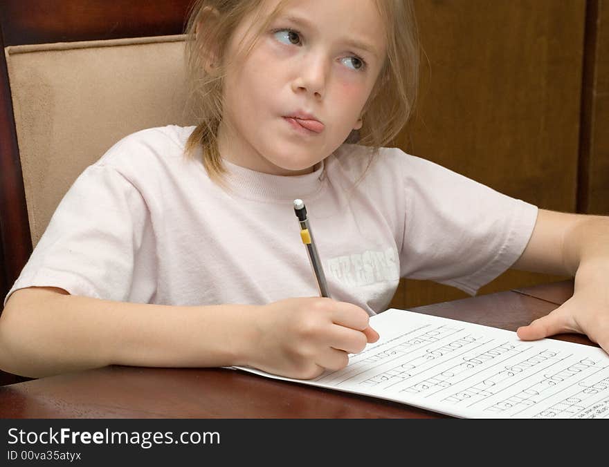 Portrait of thoughtful young girl sat at table writing homework. Portrait of thoughtful young girl sat at table writing homework.