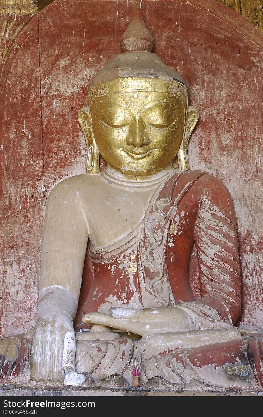 Myanmar Bagan; statue in dhammayangyi Temple; indoor archiecture and light red background for this seated buddha. Myanmar Bagan; statue in dhammayangyi Temple; indoor archiecture and light red background for this seated buddha