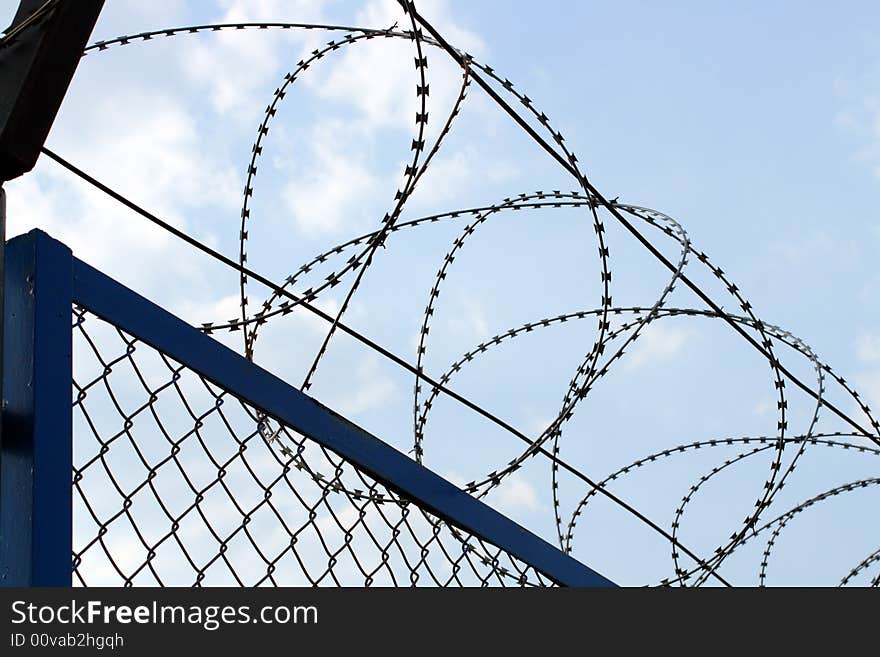 Fence with barbed wire close-up under blue sky