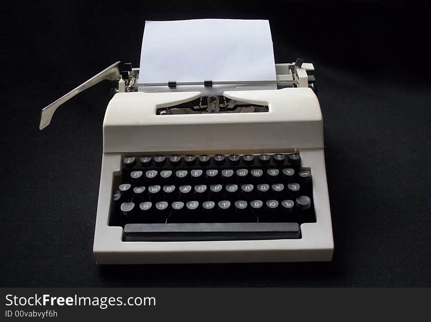 White mechanical typewriter with a paper sheet on a black background. White mechanical typewriter with a paper sheet on a black background