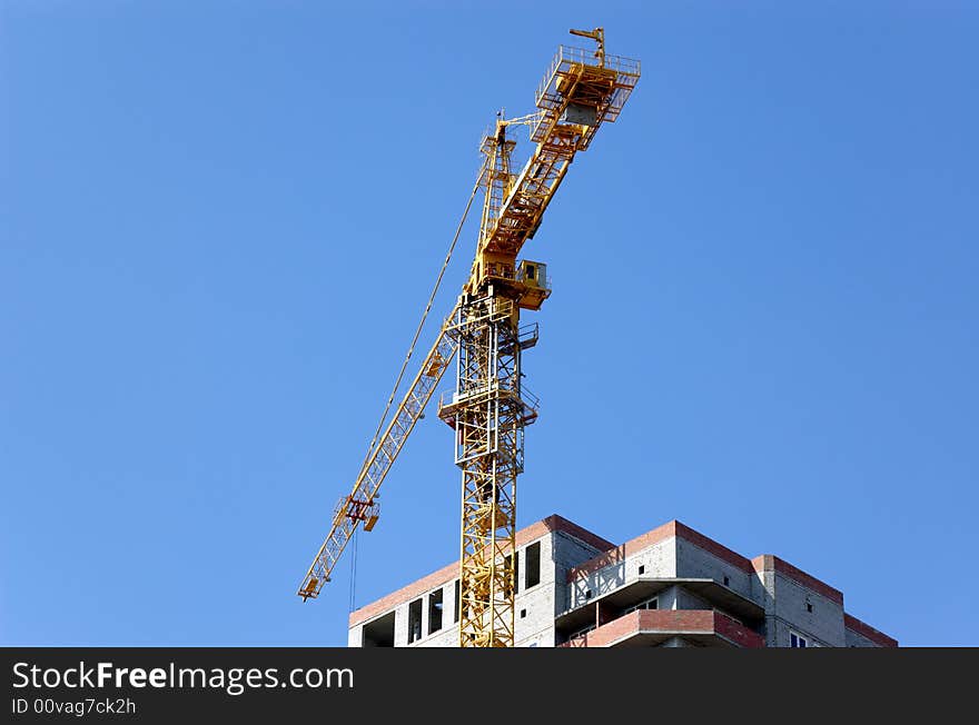 Lifting crane building the house on a blue sky