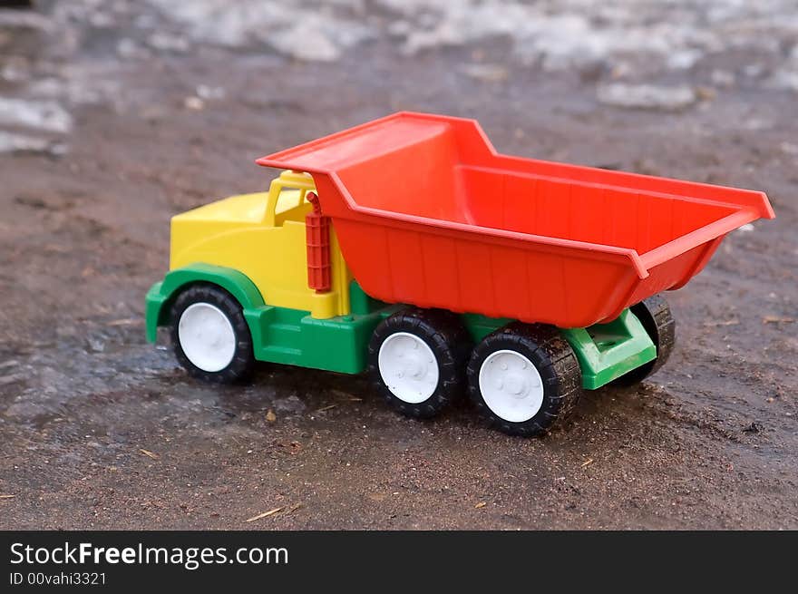 Bright baby toy dump truck in mud