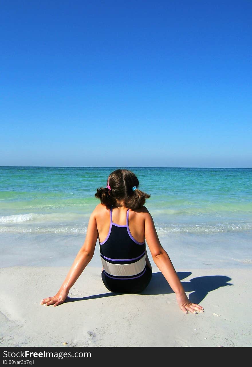 Girl sitting on the beach enjoying the sun