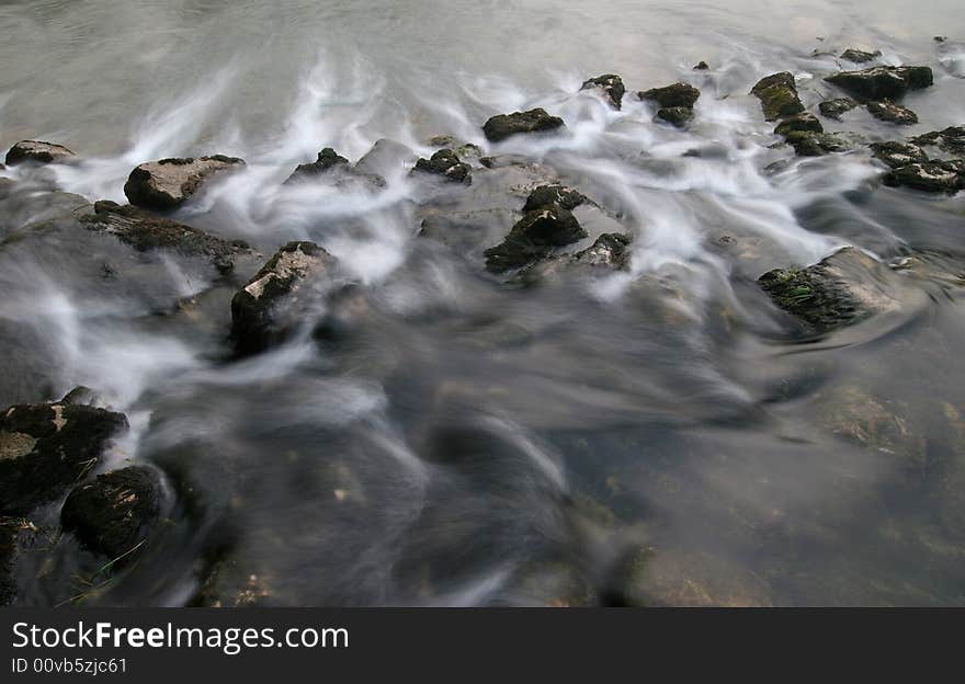 Long exposure shot of the river flowing cross the stones covered with moss. River Kolpa. Dolenjska. Slovenia