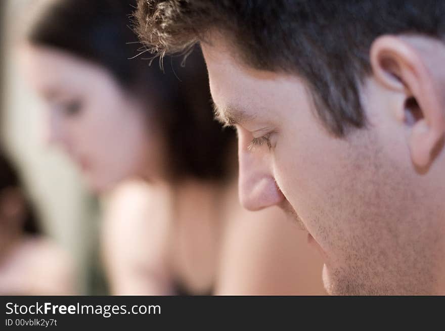 Closeup of man looking down with girl in the background.