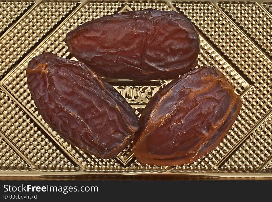 Close-up of three Tunisian dates on golden textured background