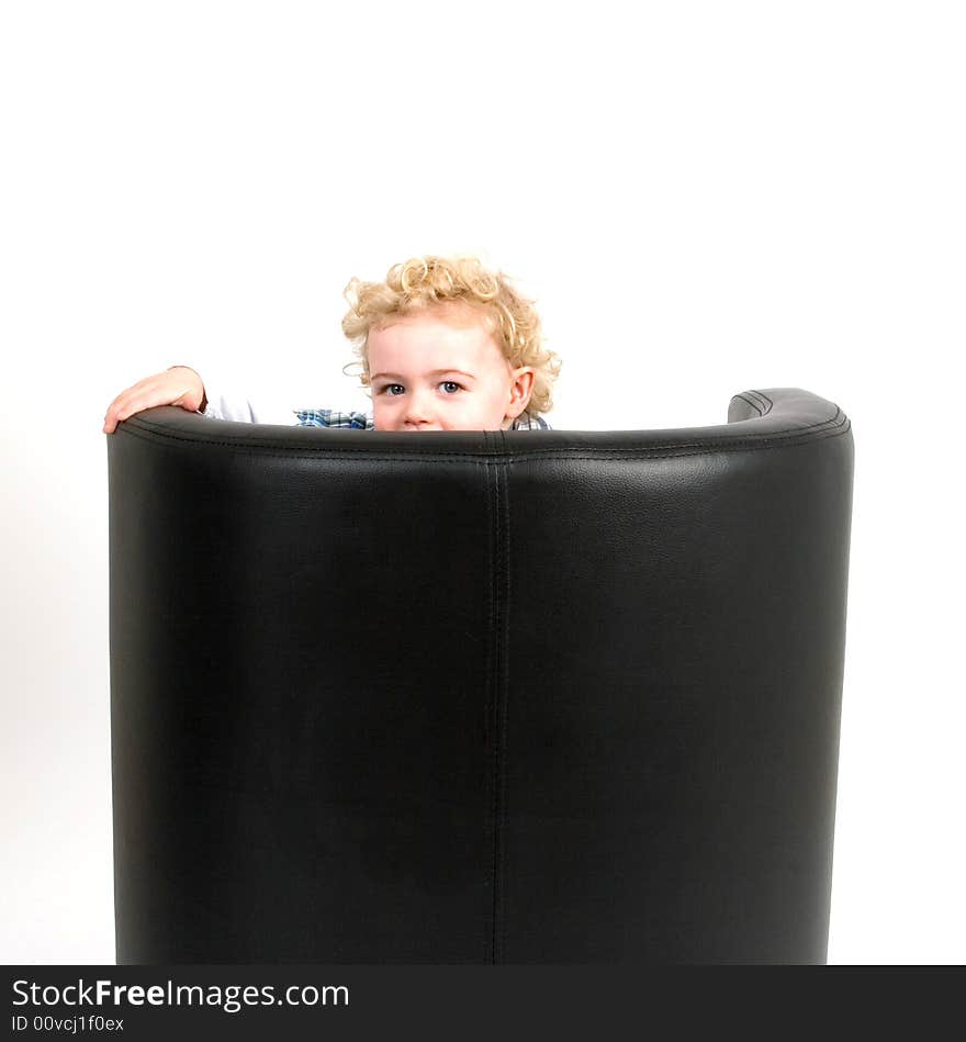 A young boy peeking from behind a chair. A young boy peeking from behind a chair