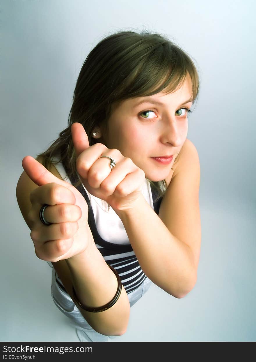 A pretty blond girl viewed from above and she shows her thumbs betoken her approval. A pretty blond girl viewed from above and she shows her thumbs betoken her approval